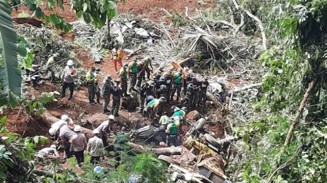 Foto: Para petugas tengah melakukan evakuasi kendaraan roda empat yang tertimbun longsor di jalan raya Cipanas-Cianjur [Suarabogor.id/Egi Abdul Mugni]