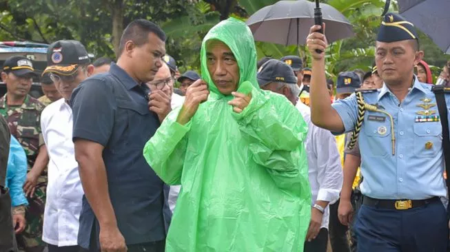 Presiden Jokowi mengenakan jas hujan plastik hijau pemberian warga saat mengunjungi korban bencana di Bojor, Januari 2020 silam. [Dok Setkab]