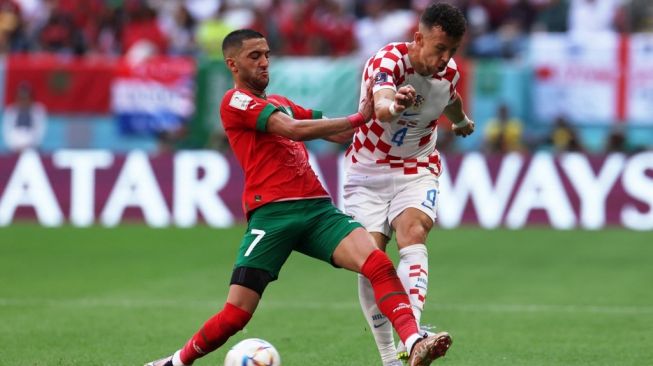 Winger Timnas Maroko, Hakim Ziyech (kiri) berebut bola dengan winger Timnas Kroasia, Ivan Perisic pada laga Piala Dunia 2022 di Stadion Al Bayt, Al Khor, Qatar, Rabu (23/11/2022) petang WIB. [FADEL SENNA / AFP]