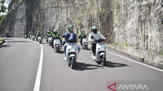 Andre Taulany (kanan) dan Surya Insomnia (kiri) berkendara bersama mitra ojek online ke Pantai Melasti, Badung, Bali, November 2022 menggunakan motor listrik untuk mengajak masyarakat beralih dari kendaraan berbahan bakar minyak ke kendaraan listrik. [ANTARA/HO- Dokumentasi Electrum].