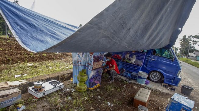 Warga memberi makan peliharanhnya saat mengungsi di mobil angkutan kota di Kampung Kuta, Cugenang, Kabupaten Cianjur, Kabupaten Bogor, Jawa Barat, Rabu (23/11/2022). [ANTARA FOTO/Yulius Satria Wijaya/foc].