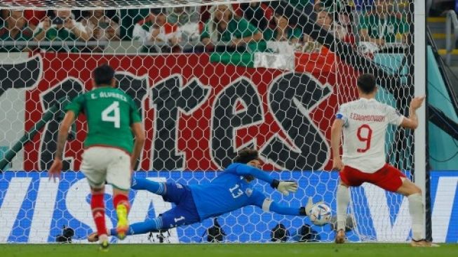 Kiper Meksiko #13 Guillermo Ochoa menggagalkan tendangan penalti penyerang Polandia #09 Robert Lewandowski pada pertandingan sepak bola Grup C Piala Dunia Qatar 2022 antara Meksiko dan Polandia di Stadion 974 di Doha pada 22 November 2022. Odd ANDERSEN / AFP