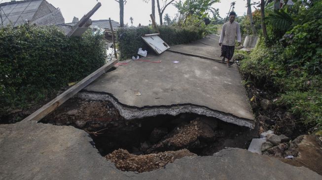 Warga melintas di jalan yang terbelah akibat gempa bumi di Sarampad, Cugenang, Kabupaten Cianjur, Jawa Barat, Rabu (23/11/2022). [ANTARA FOTO/Yulius Satria Wijaya/foc].