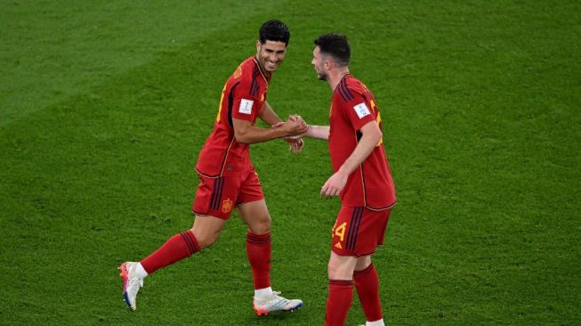 Penyerang Timnas Spanyol #10 Marco Asensio (kiri) melakukan selebrasi usai mencetak gol kedua timnya selama matchday pertama Grup E Piala Dunia 2022 Qatar antara Spanyol vs Kosta Rika di Stadion Al-Thumama di Doha pada 23 November 2022.Kirill KUDRYAVTSEV / AFP.