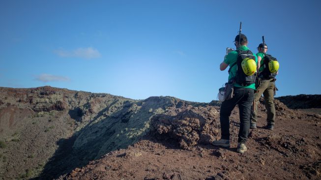 Astronot Jerman Alexander Gerst (kanan) berjalan di puncak gunung berapi purba selama program pelatihan untuk mempelajari cara menjelajahi Bulan dan Mars di Taman Nasional Timanfaya Pulau Lanzarote, Kepulauan Canary, Spanyol, Selasa (10/11/2022). [DESIREE MARTIN / AFP]
