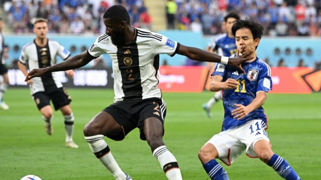 Bek Timnas Jerman, Antonio Rudiger (kiri) tampil pada laga Piala Dunia 2022 kontra Jepang di Stadion Internasional Khalifa,Qatar, Rabu (23/11/2022). [INA FASSBENDER / AFP]