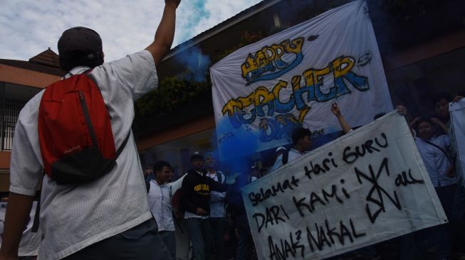 Sejumlah siswa meneriakan yel-yel dan menyalakan flare asap di sela Upacara Peringatan Hari Guru Nasional di SMK Bunda Kandung, Jakarta, Jumat (25/11/2022). [ANTARA FOTO/Indrianto Eko Suwarso/aww].