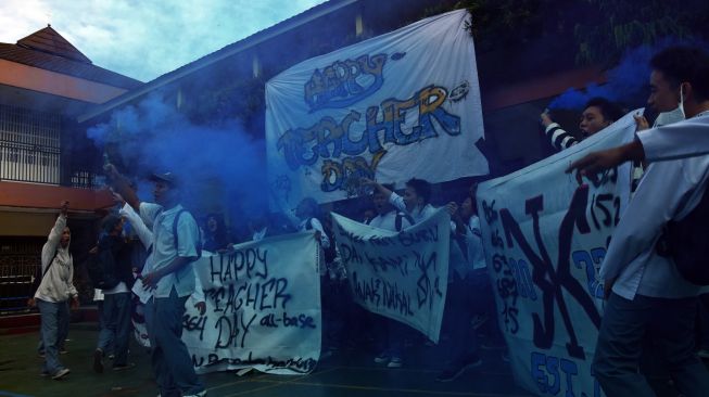 Sejumlah siswa meneriakan yel-yel dan menyalakan flare asap di sela Upacara Peringatan Hari Guru Nasional di SMK Bunda Kandung, Jakarta, Jumat (25/11/2022). [ANTARA FOTO/Indrianto Eko Suwarso/aww].