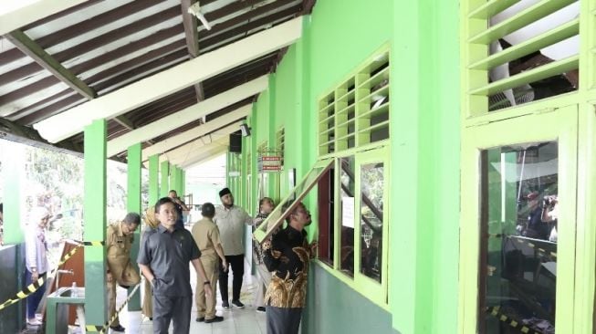 Anggota DPRD, Jatirin mengintip ruang kelas yang rusak melalui jendela. (Dok: DPRD Bogor)