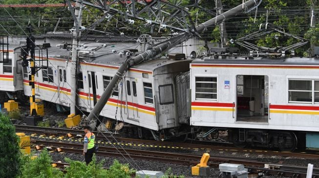 Petugas keamanan berjaga di dekat rangkaian kereta rel listrik (KRL) Commuterline KA 5144C yang anjlok dan tertimpa tiang listrik di perlintasan Stasiun Kampung Bandan, Jakarta, Sabtu (26/11/2022). [ANTARA FOTO/Aditya Pradana Putra/hp]
