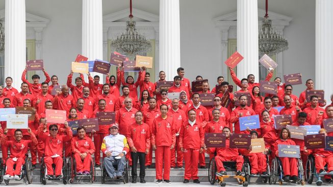 Presiden Joko Widodo (tengah) didampingi Mensesneg Pratikno (kelima kiri) dan Menpora Zainudin Amali (kelima kanan) berfoto bersama atlet dan ofisial setelah menyerahkan bonus kepada atlet ASEAN Para Games 2022 di halaman Istana Merdeka, Jakarta, Senin (28/11/2022). [ANTARA FOTO/Hafidz Mubarak A/hp]