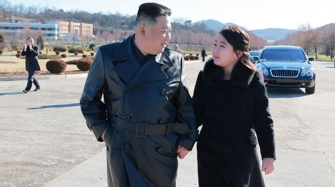 Pemimpin Korea Utara Kim Jong Un (kiri) bersama putrinya (kanan) saat mereka mengunjungi tentara yang berkontribusi uji coba rudal balistik antarbenua (ICBM) Hwasong-17 di lokasi rahasia, dalam foto tak bertanggal yang rilis pada Minggu (27/11/2022). [KCNA VIA KNS / AFP]
