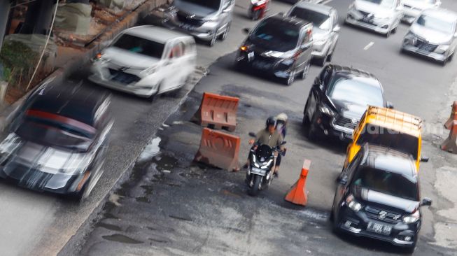 Kendaraan melintasi jalan rusak di sekitar Pembangunan Stasiun LRT, Jalan Rasuna Said, Jakarta Selatan, Rabu (30/11/2022). [Suara.com/Alfian Winanto]