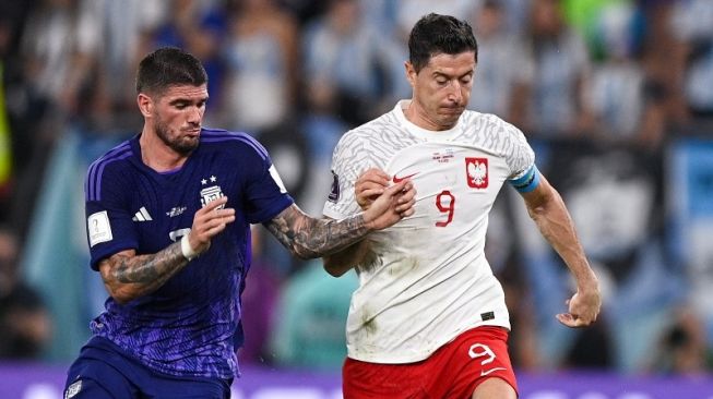 Gelandang Timnas Argentina, Rodrigo de Paul (kiri) bersaing memperebutkan bola dengan striker Timnas Polandia, Robert Lewandowski selama matchday ketiga Grup C di Stadion 974, Doha, Qatar, Kamis (1/12/2022) dini hari WIB. Argentina pada akhirnya menang 2-0 atas Polandia dan berhak lolos ke babak 16 besar. [FIFA]