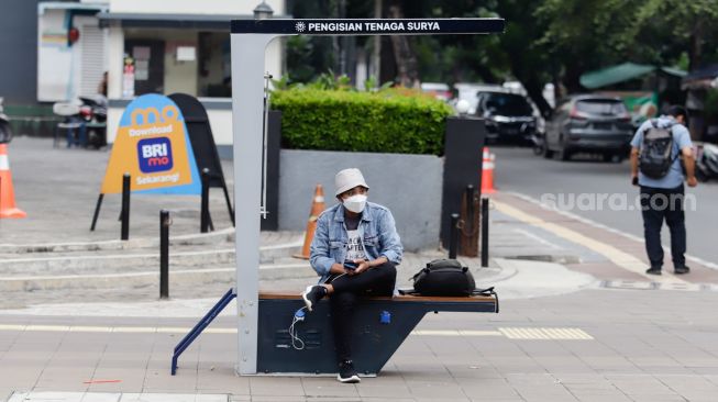 Warga mengisi daya gawainya di stasiun pengisi daya listrik bertenaga surya di kawasan Dukuh Atas, Jakarta Pusat, Senin (14/11/2022). [Suara.com/Alfian Winanto]