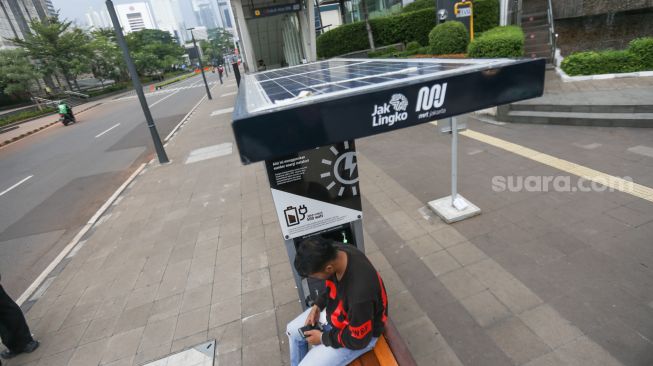 Warga mengisi daya gawainya di stasiun pengisi daya listrik bertenaga surya di kawasan Dukuh Atas, Jakarta Pusat, Senin (14/11/2022). [Suara.com/Alfian Winanto]