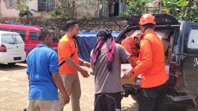 Penduduk sekitar membantu Tim Search and Rescue (SAR) Astra mendistribusikan paket bantuan untuk masyarakat terdampak bencana gempa bumi di Desa Wangun Jaya, Cianjur, Jawa Barat [Nurani Astra].