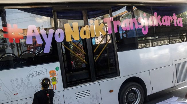 Anak berkebutuhan khusus melukis pada badan bus Transjakarta di Kantor Pusat Transjakarta, Cawang, Jakarta, Kamis (1/12/2022). [ANTARA FOTO/Darryl Ramadhan/nym].