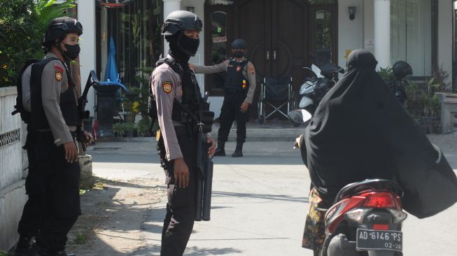 Anggota Polri bersenjata lengkap berjaga di sekitar tempat tinggal terduga teroris berinisial JU di Ngruki, Cemani, Grogol, Sukoharjo, Jawa Tengah, Kamis (1/12/2022). [ANTARA FOTO/Aloysius Jarot Nugroho/rwa].