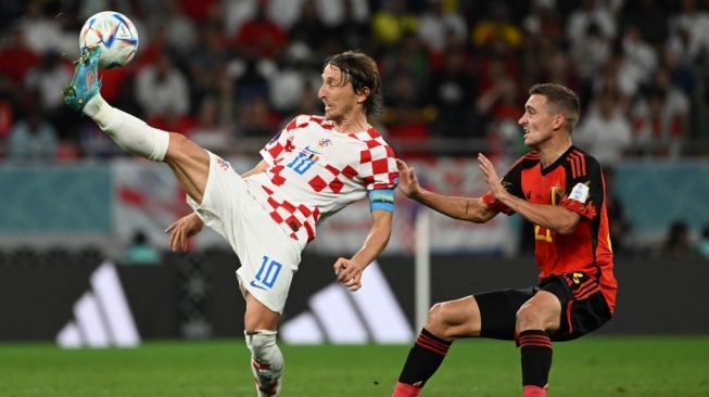 Gelandang Timnas Kroasia, Luka Modric (kiri) berebut bola dengan bek sayap Timnas Belgia, Timothy Castagne pada laga Piala Dunia 2022 di Stadion Ahmed bin Ali, Qatar, Kamis (1/12/2022) malam WIB. [OZAN KOSE / AFP]