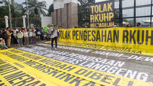 Massa saat menggelar aksi unjuk rasa menolak pengesahan RKUHP di depan Gedung DPR RI, Senayan, Jakarta Pusat, Senin (5/12/2022). [Suara.com/Alfian Winanto]