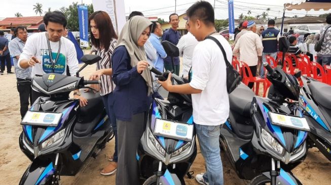 Petugas PLN UP3 Tanjungpinang mengenalkan sepeda motor listrik kepada warga di Tanjunguban, Kabupaten Bintan, Kepri, Minggu (4/12) [ANTARA/Ogen].