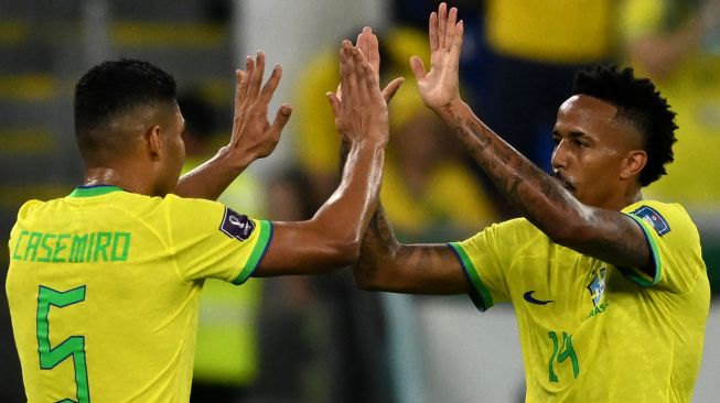 Bek Brazil Eder Militao menyapa gelandang Brazil Casemiro saat ia digantikan oleh bek Brazil Dani Alves saat pertandingan sepak bola babak 16 besar Piala Dunia 2022 antara Brazil dan Korea Selatan di Stadion 974 di Doha, Qatar, Senin (5/12/2022). [Pablo PORCIUNCULA/AFP]