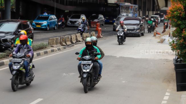 Ojek online melintas di Jalan Rasuna Said, Jakarta Selatan, Selasa (6/12/2022). [Suara.com/Alfian Winanto]