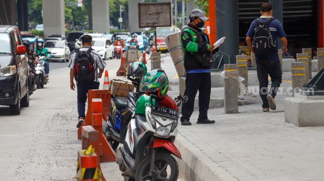 Ojek online mengantar barang di Jalan Rasuna Said, Jakarta Selatan, Selasa (6/12/2022). [Suara.com/Alfian Winanto]