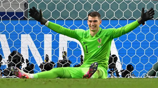 Kiper Kroasia Dominik Livakovic selebrasi usai berhasil melakukan penyelamatan ketika babak adu penalti saat pertandingan sepak bola babak 16 besar Piala Dunia 2022 antara Jepang dan Kroasia di Stadion Al-Janoub di Al-Wakrah, selatan Doha, Qatar, Senin (5/12/2022). [OZAN KOSE/AFP]