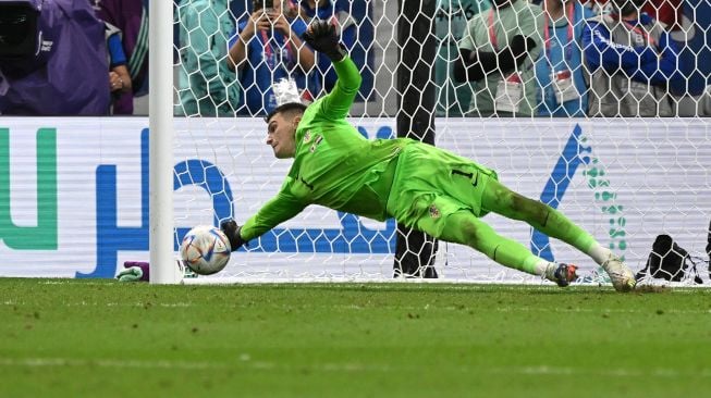 Kiper Kroasia Dominik Livakovic berhasil menghalau bola tendangan ketika babak adu penalti saat pertandingan sepak bola babak 16 besar Piala Dunia 2022 antara Jepang dan Kroasia di Stadion Al-Janoub di Al-Wakrah, selatan Doha, Qatar, Senin (5/12/2022). [ANDREJ ISAKOVIC / AFP]