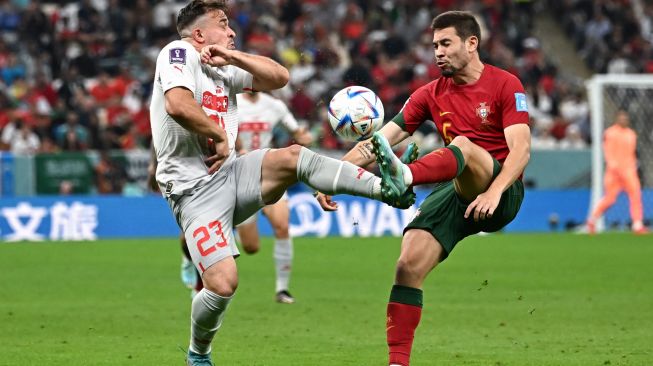 Gelandang Swiss Xherdan Shaqiri dan bek Portugal Raphael Guerreiro memperebutkan bola saat pertandingan sepak bola babak 16 besar Piala Dunia 2022 antara Portugal dan Swiss di Stadion Lusail di Lusail, utara Doha, Qatar, Selasa (6/12/2022). [Anne-Christine POUJOULAT / AFP]