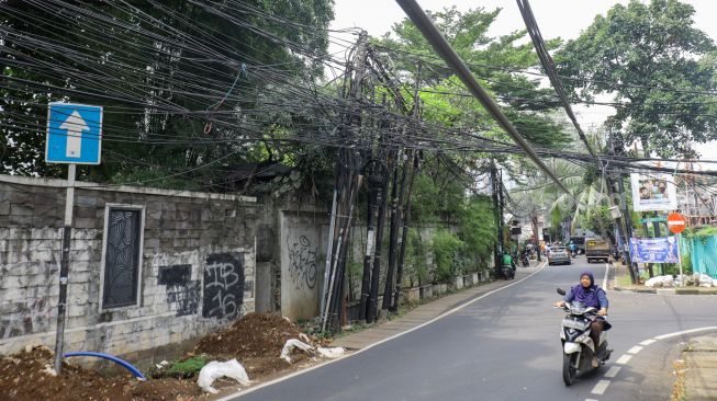 Instalasi kabel yang semrawut terlihat di Jalan Kemang Utara, Mampang Prapatan, Jakarta Selatan, Rabu (7/12/2022). [Suara.com/Alfian Winanto]