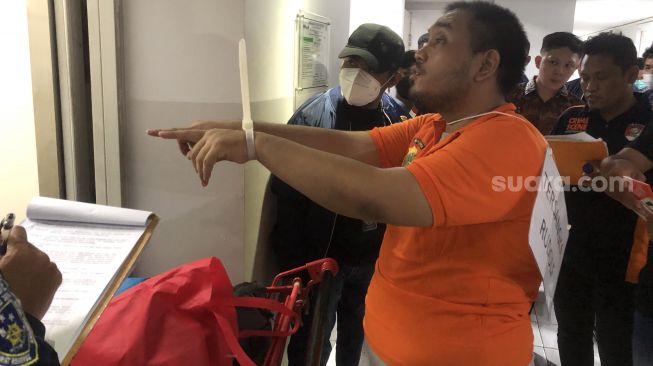 Christian Rudolf Tobing, eks pendeta muda saat menjalani rekonstruksi kasus pembunuhan di Apartemen Green Pramuka, Jakarta Pusat. (Suara.com/Faqih)