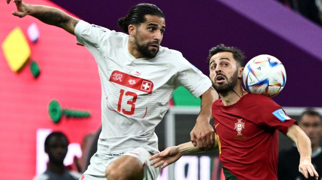 Bek Swiss Ricardo Rodriguez dan gelandang Portugal Bernardo Silva memperebutkan bola saat pertandingan sepak bola babak 16 besar Piala Dunia 2022 antara Portugal dan Swiss di Stadion Lusail di Lusail, utara Doha, Qatar, Selasa (6/12/2022). [Permata SAMAD / AFP]