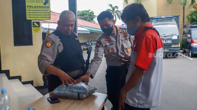 Polisi memeriksa barang bawaan pengunjung di area Polres Jakarta Selatan, Rabu (7/12/2022). [Suara.com/Alfian Winanto]