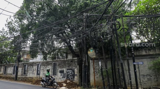 Instalasi kabel yang semrawut terlihat di Jalan Kemang Utara, Mampang Prapatan, Jakarta Selatan, Rabu (7/12/2022). [Suara.com/Alfian Winanto]