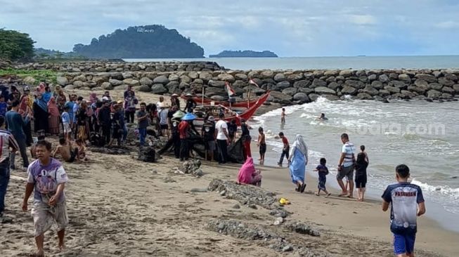 Masyarakat yang menunggu tukang elo pukek menarik tangkapan ikannya di pantai Padang. [Suara.com/Riki Chandra]