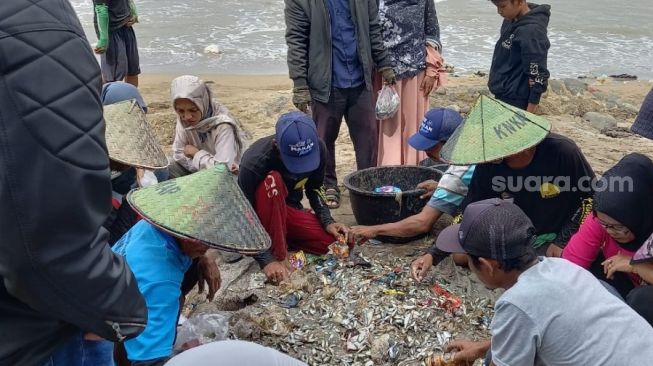 Masyarakat menyaksikan tukang elo pukek membersihkan ikan hasil mamukek di Pantai Purus, Kota Padang. [Suara/Riki Chandra]