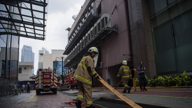 Petugas pemadam kebakaran menarik selang air usai memadamkan kebakaran di Kantor Kemenkumham, Jalan Rasuna Said, Jakarta Selatan, Kamis (8/12/2022). [ANTARA FOTO/Sigid Kurniawan]