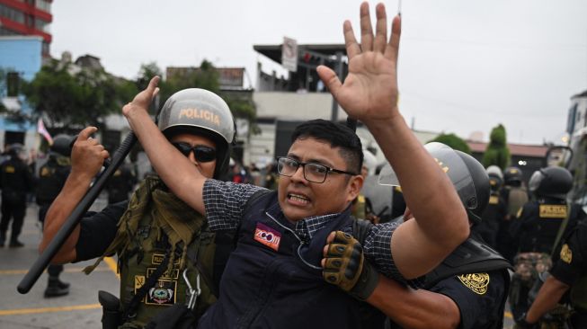 Seorang pendukung mantan Presiden Peru Pedro Castillo dibawa pergi oleh polisi di pinggiran Prefektur Lima tempat Castillo ditahan, di Lima, Peru, Rabu (7/12/2022). [ERNESTO BENAVIDES / AFP]