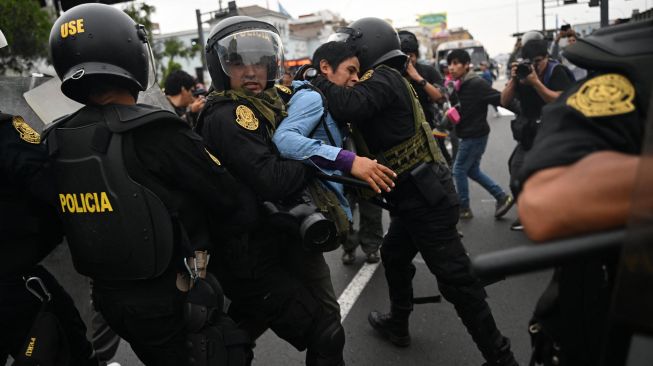 Seorang pendukung mantan Presiden Peru Pedro Castillo dibawa pergi oleh polisi di pinggiran Prefektur Lima tempat Castillo ditahan, di Lima, Peru, Rabu (7/12/2022). [ERNESTO BENAVIDES / AFP]