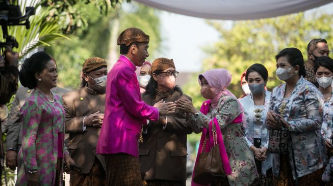 Presiden Joko Widodo (ketiga kiri) bersama Ibu Negara Iriana Joko Widodo (kiri) menyalami kerabat sebelum prosesi memasang "bleketepe" di atas gerbang kediamannya, di Jalan Kutai Utara, Sumber, Banjarsari, Solo, Jawa Tengah, Jumat (9/12/2022).[ANTARA FOTO/Mohammad Ayudha].