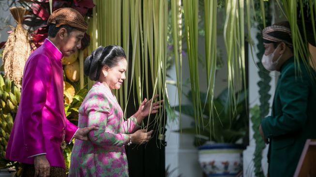 Presiden Joko Widodo (kiri) bersama Ibu Negara Iriana Joko Widodo (kanan) memasuki kediaman usai prosesi pemasangan "bleketepe" di atas gerbang kediamannya, di Jalan Kutai Utara, Sumber, Banjarsari, Solo, Jawa Tengah, Jumat (9/12/2022). [ANTARA FOTO/Mohammad Ayudha].