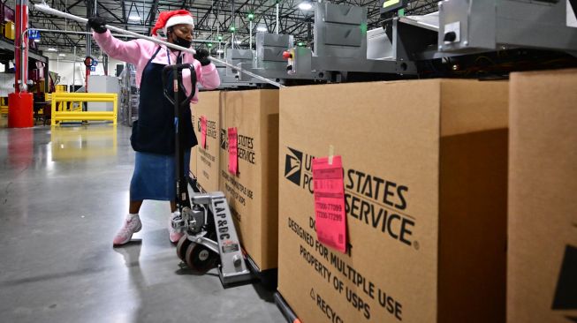 Karyawan Kantor Pos mengenakan topi Sinterklas saat menyortir surat di Pusat Pemrosesan dan Distribusi Los Angeles, Amerika Serikat, Rabu (30/11/2022). [Frederic J. BROWN / AFP]