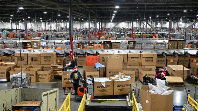 Karyawan Kantor Pos mengenakan topi Sinterklas saat menyortir surat di Pusat Pemrosesan dan Distribusi Los Angeles, Amerika Serikat, Rabu (30/11/2022). [Frederic J. BROWN / AFP]