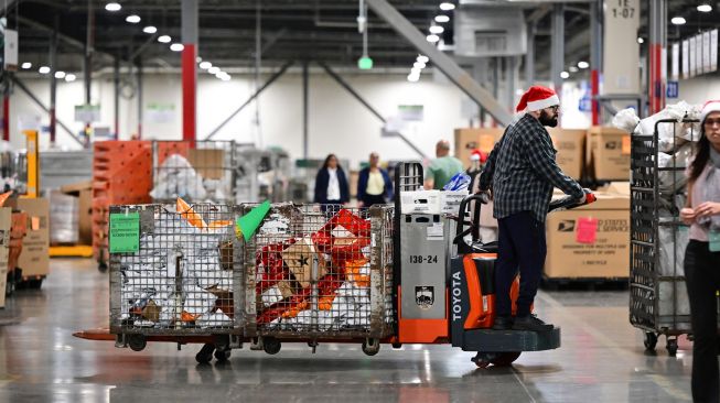 Karyawan Kantor Pos mengenakan topi Sinterklas saat menyortir surat di Pusat Pemrosesan dan Distribusi Los Angeles, Amerika Serikat, Rabu (30/11/2022). [Frederic J. BROWN / AFP]