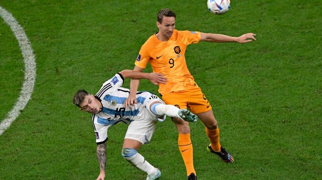 Bek Argentina Lisandro Martinez (kiri) berebut bola dengan penyerang Belanda Luuk De Jong saat pertandingan sepak bola perempat final Piala Dunia 2022 antara Belanda dan Argentina di Stadion Lusail, utara Doha, Qatar, Jumat (9/12/2022). [PATRICIA DE MELO MOREIRA/AFP]
