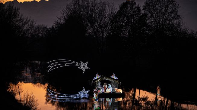 Instalasi Natal yang berkisah tentang kelahiran Yesus di sungai Po, Villafranca Piemonte, dekat Turin, Italia, Selasa (6/12/2022). [MARCO BERTORELLO / AFP]