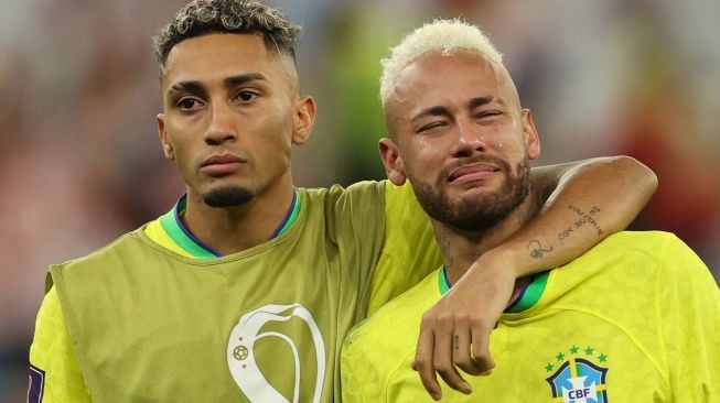 Penyerang Brazil Neymar menangis dan dihibur oleh penyerang Brazil Raphinha setelah tim mereka kalah dalam pertandingan sepak bola perempat final Piala Dunia 2022 antara Kroasia dan Brazil di Stadion Education City di Al-Rayyan, barat Doha, Qatar, Jumat (9/12/2022). [Adrian DENNIS/AFP]